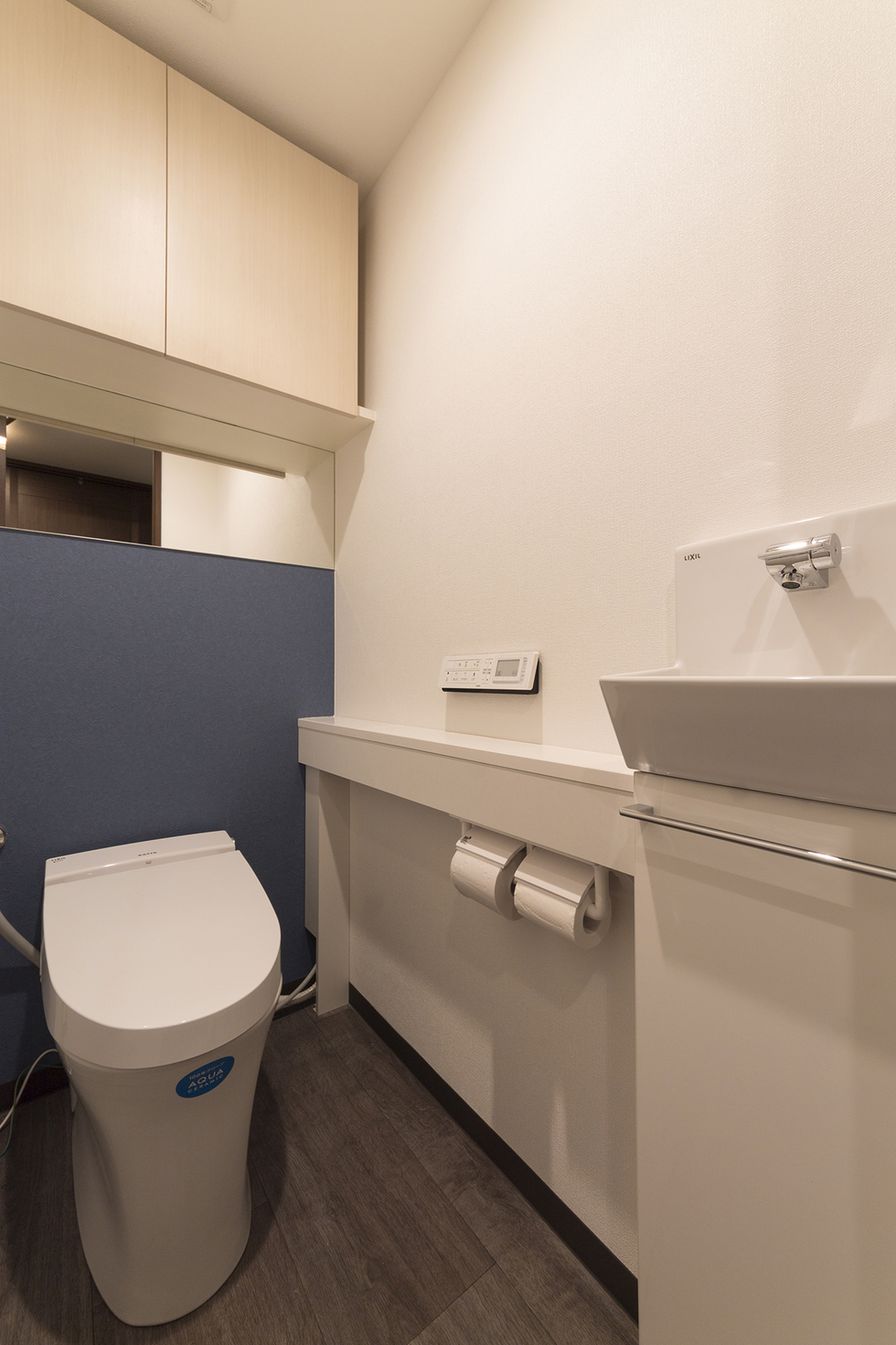 -マンションのキッチン・浴室・洗面・トイレリフォーム-広めの空間を生かして手洗いカウンターを設けました。
床は木目を生かしたナチュラルな雰囲気とし、正面にブルーグレーの壁紙でアクセントを付けました。